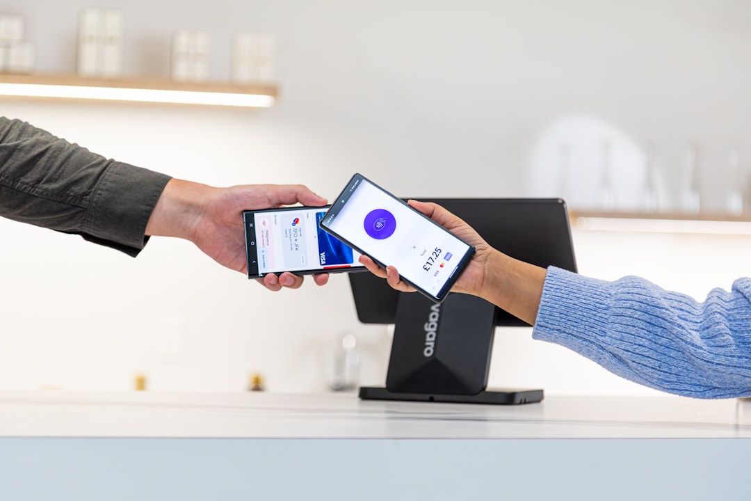 At the front desk of a beautifully lit salon, a customer pays for a service in front of a Vagaro PayPro. The space is clean and white which makes the black hardware stand out.